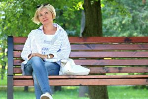 mature woman looking thoughtful on bench