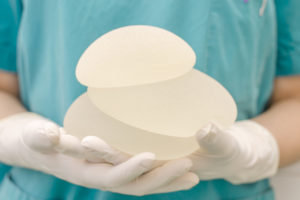 Medical doctor holding a stack of different sized breast implants.