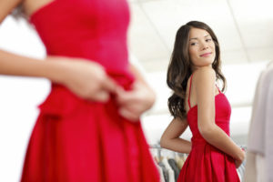Woman trying on red dress looking in the mirror.