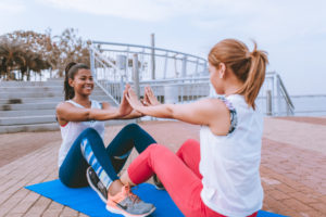 Two women working out together on the boardwalk.