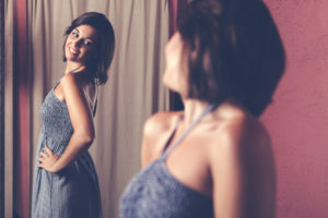 Woman looking at her oufit in the mirror.